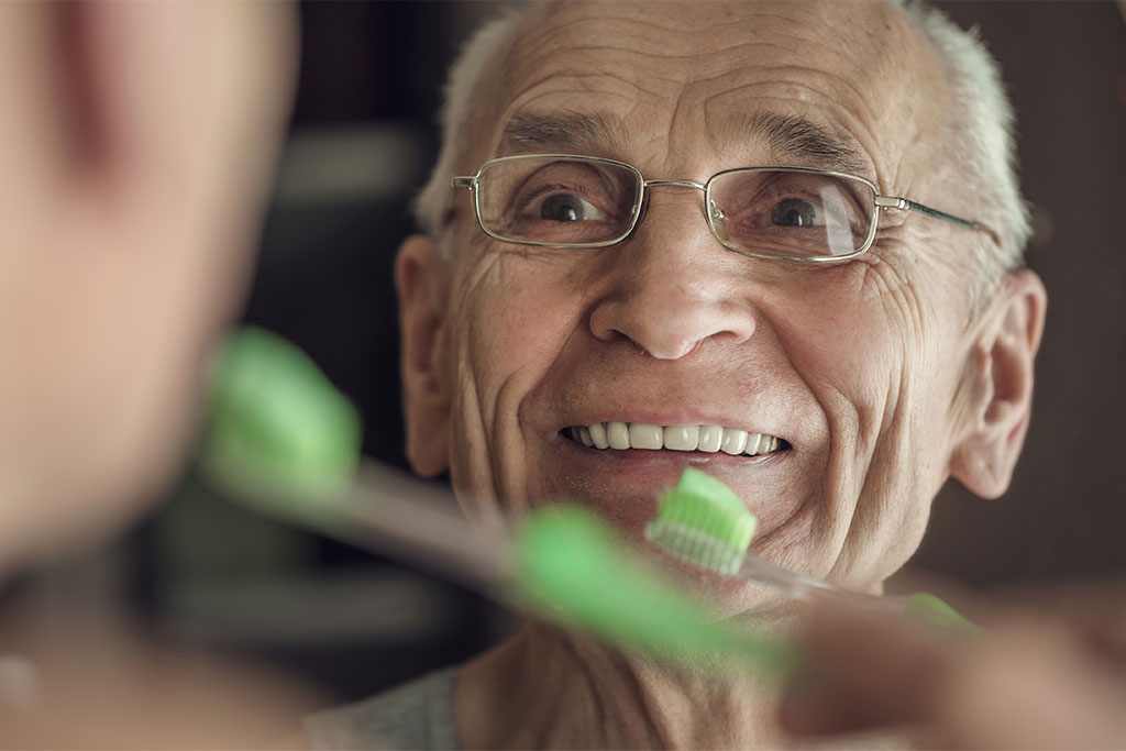 Homme âgé souriant avec une dentition parfaite grâce aux prothèses amovibles de votre cabinet Joli-Bois.