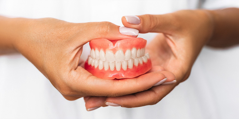 Exemple d'un dentier tenu en main par une dentiste.